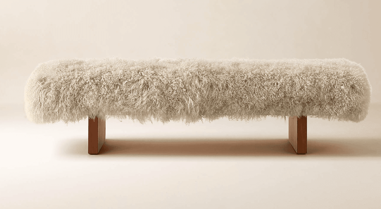 A contemporary bench featuring a long, cylindrical seating surface fully upholstered in white, shaggy faux fur. The bench is supported by two minimalist rectangular wooden slab legs, positioned near each end of the upholstered top. — 3D model