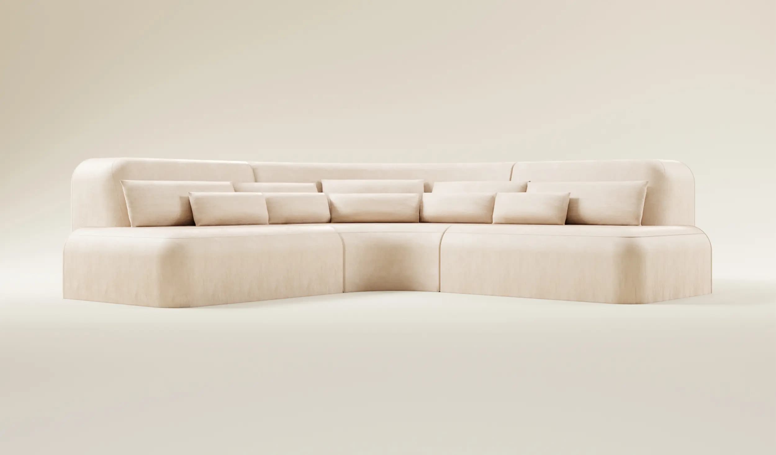 A modular, sectional sofa with a curved design and plush upholstery. It features a low profile with rounded corners and is complemented by multiple scatter cushions. The sofa appears to be constructed from a fabric material and is arranged in an L-shape. — 3D model