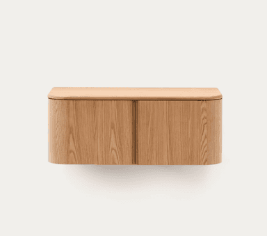 A wall-mounted wooden cabinet with a minimalist design. It features two cabinet doors with a vertical wood grain pattern and rounded side edges. The top surface is flat and also has rounded edges, suggesting a continuous curved form around the sides. — 3D model