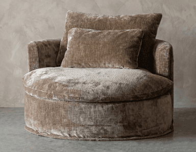 An oversized, round lounge chair upholstered in a plush, textured taupe velvet fabric. The chair features a deep, comfortable seat cushion and a rounded, integrated backrest and arms, forming a barrel-like silhouette. It comes with two additional rectangular throw pillows in the same material, enhancing comfort and aesthetic appeal. The overall design emphasizes softness and a luxurious feel. — 3D model