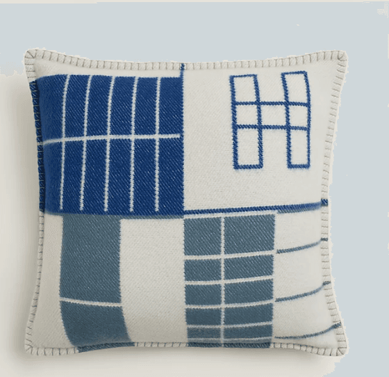 A square cushion with a geometric pattern. The pattern consists of blocks of blue and white with white grid lines. The edges are finished with a contrasting stitch. — 3D model