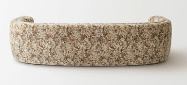 A curved sofa upholstered in a textured fabric with an abstract pattern. The sofa features rounded arms that seamlessly integrate into the backrest, creating a continuous, organic form. The seat is composed of a single cushion, and the backrest is also a continuous curve. The upholstery displays a mélange of colors including cream, beige, brown, and subtle hints of red and green. — 3D model