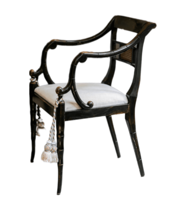 An armchair featuring an ebonized, faux bamboo-style wooden frame. The backrest includes a rectangular woven cane panel, while the arms are elegantly curved, flowing from the back. The seat is upholstered in a light-colored, possibly off-white or cream, fabric. The legs are tapered and also mimic the bamboo motif, with the front legs adorned with decorative tassels. The overall aesthetic suggests a Regency or Chinoiserie influence. — 3D model
