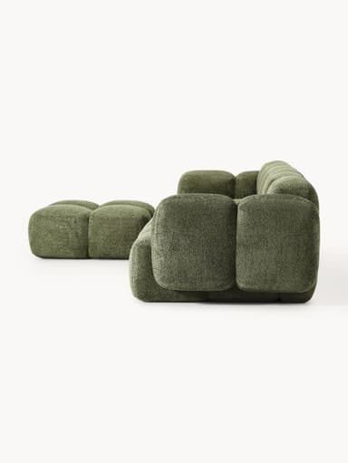 A modular sectional sofa composed of multiple cubic upholstered units. The sofa features a low profile and rounded edges on each module, creating a soft, organic aesthetic. It is upholstered in a textured, boucle-like fabric in a muted green hue. The arrangement suggests a configuration that includes a corner section and extended seating. — 3D model