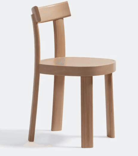 A light-colored wooden chair featuring a minimalist design with a round seat, thick cylindrical legs, and a simple, curved backrest. — 3D model