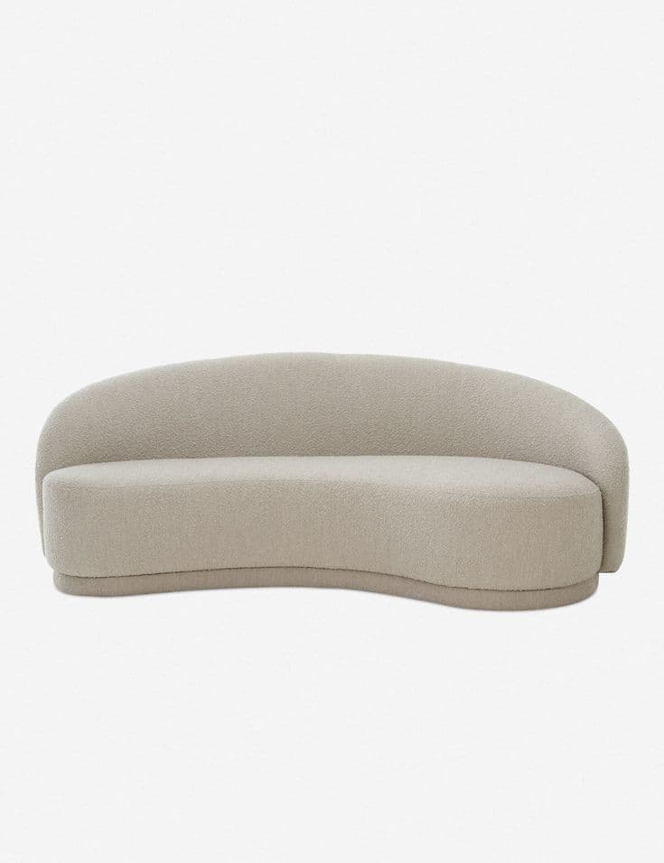 A contemporary curved sofa upholstered in a light beige bouclé fabric, featuring a continuous low-slung backrest and an integrated, recessed base. — 3D model