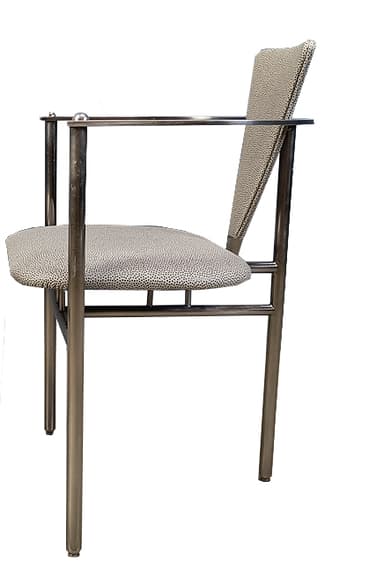 A modern armchair with a tubular metal frame and upholstered seat and backrest. The frame is constructed from polished chrome or stainless steel, featuring cylindrical legs and armrests. The seat and backrest are upholstered in a light-colored fabric with a speckled pattern. The design is minimalist and functional. — 3D model