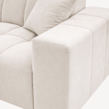 A contemporary sectional sofa with a tufted upholstery design. The sofa features a chaise lounge section extending from the main body. It is upholstered in a light cream-colored fabric with a soft texture. The design incorporates horizontal tufting on the seat and back cushions, creating a grid-like pattern. Two square throw pillows, matching the sofa's upholstery, are placed on the sofa. The sofa sits on low-profile, dark-colored feet. — 3D model