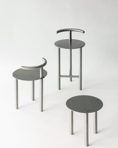 A modern bar stool with a circular seat, three cylindrical legs, and a curved backrest support. The seat has three circular indentations for decorative or functional purposes. The legs are connected by a horizontal crossbar for stability. — 3D model