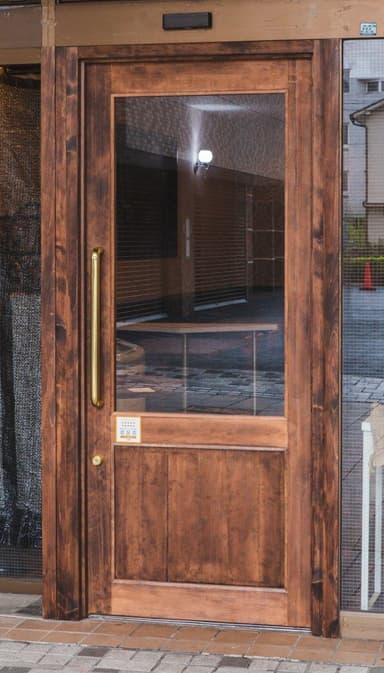 A wooden door with a glass pane and a brass handle. The door features a central vertical wooden panel below a larger rectangular glass insert. The wooden frame has a subtle beveled edge detail. A gold-toned pull handle is mounted horizontally on the right side, and a small round knob or lock escutcheon is visible lower down. — 3D model