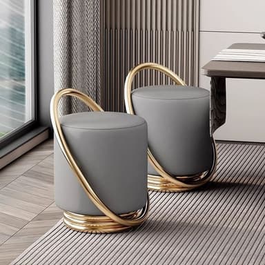 A contemporary cylindrical ottoman featuring soft grey upholstery and a distinctive, curvilinear gold-toned metallic frame that wraps around its body and base. — 3D model