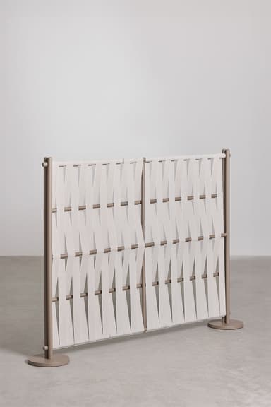 A modern freestanding room divider composed of two rectangular panels. Each panel features a tubular metal frame in a matte taupe color, with horizontal rods through which wide, off-white textile straps are woven in a diagonal, crisscrossing pattern. The divider stands on two flat, circular bases, one at each end. — 3D model