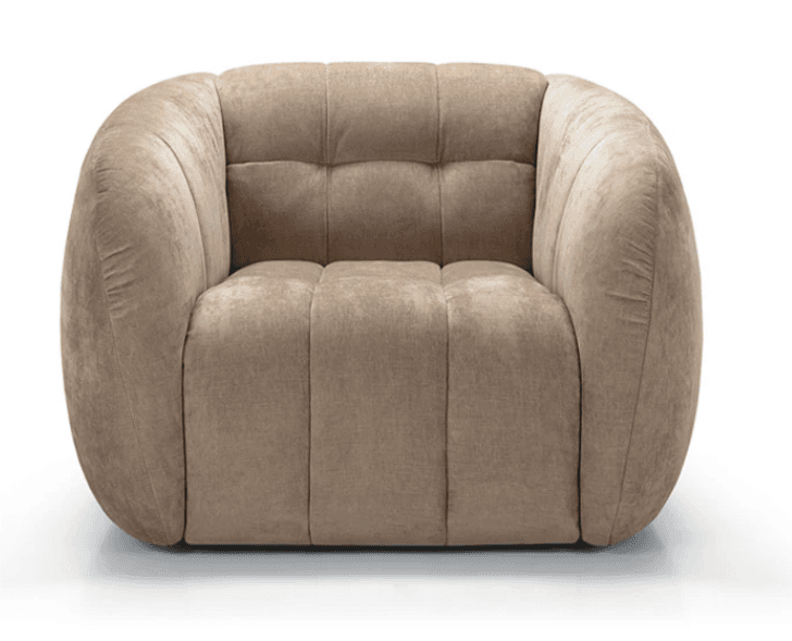 A single contemporary accent chair featuring a rounded, barrel-like silhouette. The chair is upholstered in a soft, beige velvet or velour fabric. It has distinct channel tufting on the arms and sides, which contributes to its plush appearance, and button tufting on the backrest. The base is recessed, giving the chair a floating effect. Its overall design emphasizes comfort and a modern aesthetic. — 3D model