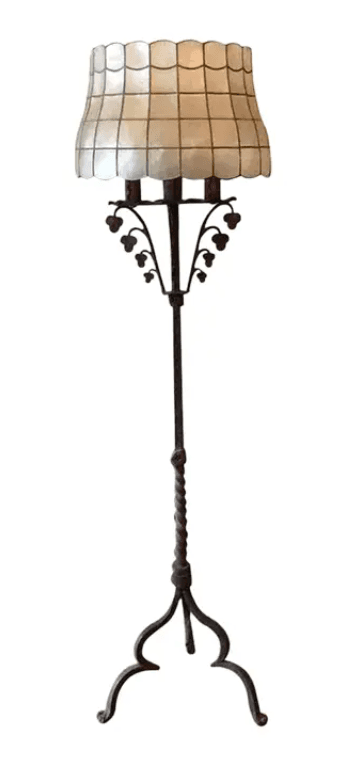 A floor lamp with a decorative, scalloped lampshade composed of square mother-of-pearl or similar material panels framed by dark metal grid. The lampshade is supported by an ornate, dark metal stem that features leaf-like decorative elements. The stem tapers down to a twisted section above a tripod base with elegantly curved legs. — 3D model