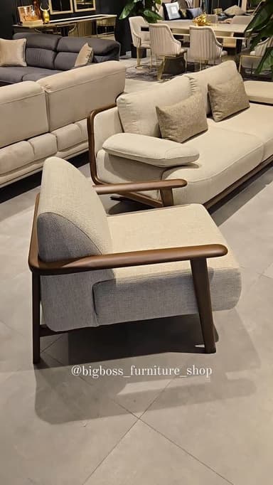 A modern upholstered armchair featuring an exposed dark wood frame that forms the armrests and supports the seat. The upholstery is a light, neutral fabric, likely cream or off-white, with a subtle textured weave. The chair has a relatively compact footprint with a slightly angled backrest and straight legs, suggesting a comfortable yet refined seating position. — 3D model