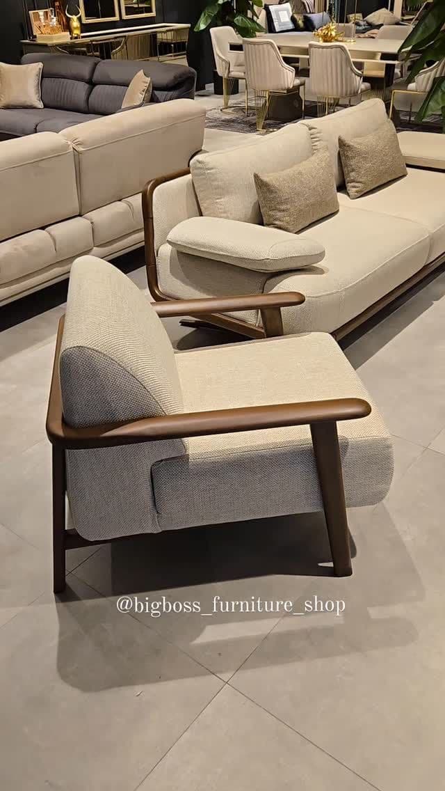 A modern upholstered armchair featuring an exposed dark wood frame that forms the armrests and supports the seat. The upholstery is a light, neutral fabric, likely cream or off-white, with a subtle textured weave. The chair has a relatively compact footprint with a slightly angled backrest and straight legs, suggesting a comfortable yet refined seating position. — 3D model