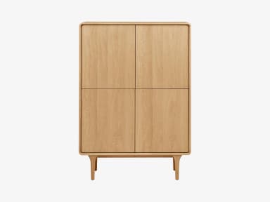 A freestanding, light-toned wooden storage cabinet featuring four solid doors arranged in a two-by-two configuration. The cabinet has gently rounded corners on its top and sides and stands on four splayed, tapered legs that are integrated into a plinth-like base. — 3D model
