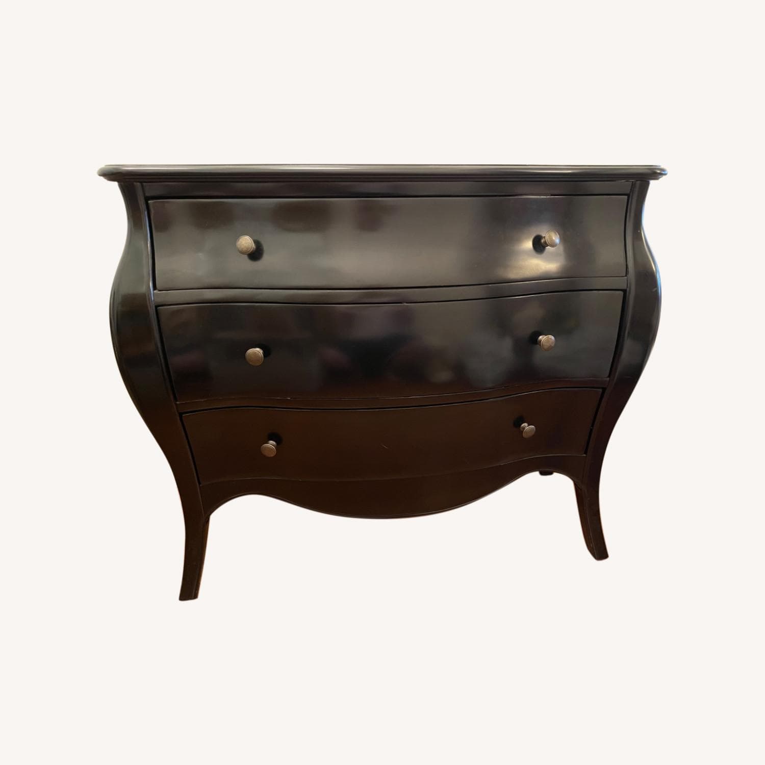 A dark-finished bombe chest of drawers featuring a serpentine top and three bowed drawers, each fitted with antique-style metal knobs. The chest exhibits a curvilinear silhouette with gracefully curved sides and subtle cabriole-style legs, indicative of a Rococo or French Provincial design. — 3D model