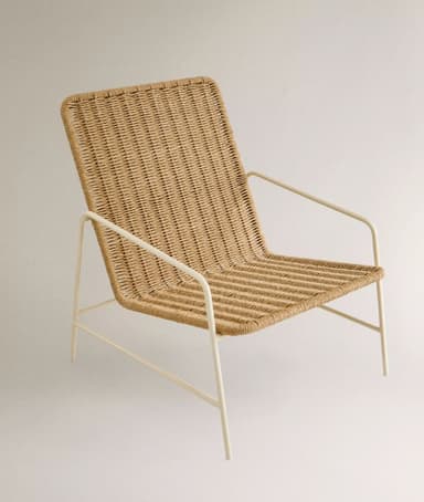 A lounge chair featuring a natural woven rattan seat and back, supported by a slender, light-colored metal frame with integrated armrests. The design is minimalist and contemporary. — 3D model