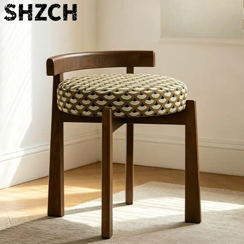 A compact vanity stool featuring a dark brown walnut wood frame and a circular, generously upholstered seat. The upholstery has a distinctive geometric scallop pattern in shades of olive green, cream, and dark brown. It includes a minimal, curved wooden backrest that extends from the rear legs. The legs are slightly tapered and square in profile. — 3D model