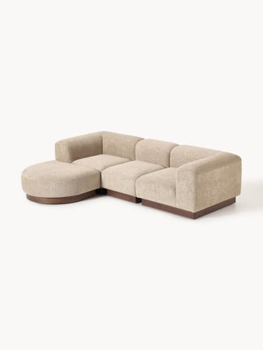 A sectional sofa composed of three distinct modules, including a curved corner piece, an armless central piece, and an end piece with an armrest. The sofa features a textured, boucle-like fabric upholstery and a dark wooden plinth base. — 3D model