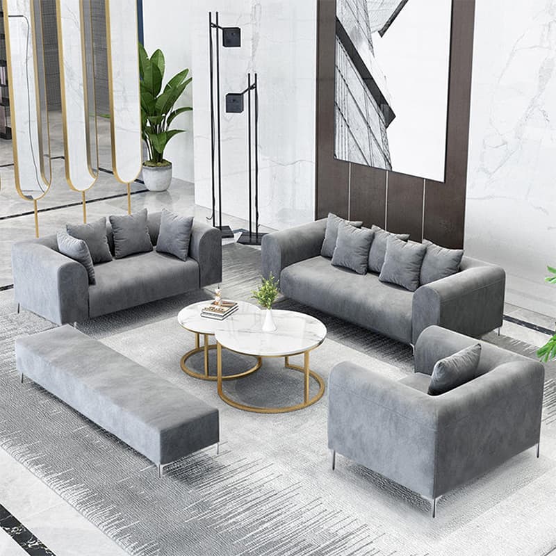 A modern, three-seater sofa upholstered in a grey fabric, featuring rounded track arms, loose back cushions, and slender, minimalist metal legs. It includes additional throw pillows for comfort. — 3D model