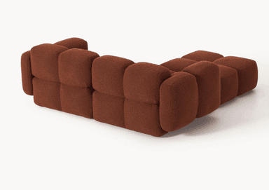 A modular sofa with a rounded, organic silhouette. The sofa is composed of several individual cubic modules that are upholstered in a textured, bouclé fabric. The arrangement suggests a sectional configuration, possibly an L-shape, with distinct seat and backrest sections, and padded armrests. The overall design is characterized by its plush, pillow-like appearance and low profile. — 3D model