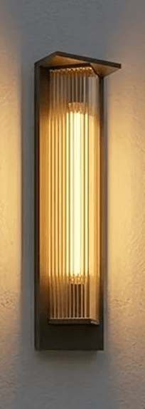 A tall, rectangular wall-mounted light fixture featuring a dark-toned metal backplate and a prominent fluted glass diffuser. The glass section is ribbed vertically and appears to be illuminated from within, casting a warm glow. The top of the metal frame and glass diffuser show an angular, stepped design, giving it a distinct Art Deco or classic modern aesthetic. The light is shown mounted on a textured, light-colored wall. — 3D model