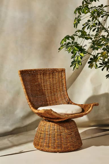 A contemporary lounge chair crafted from natural woven rattan, featuring a wide, curving backrest and a conical base that allows for 360-degree swivel movement. It includes a round, off-white seat cushion for added comfort. — 3D model