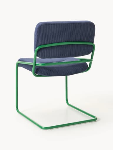 A side profile view of a modern accent chair. The chair features a tubular metal frame, painted in a vibrant green, forming cantilevered legs and armrests. The seat and backrest are upholstered in a navy blue corduroy fabric with a ribbed texture. The seat is slightly tufted. — 3D model
