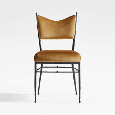 A chair with a dark, metallic frame and a cushioned seat and back. The frame appears to be wrought iron or a similar metal, with four slender legs and a simple stretcher system. The backrest is slightly curved and has a distinctive shape, reminiscent of a butterfly or a stylized 'W'. The upholstery is a rich, golden-brown velvet fabric. — 3D model