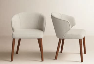 An upholstered armchair featuring a rounded, continuous backrest that flows into integrated armrests. The seat is padded, and the chair is supported by four splayed, tapered wooden legs. — 3D model