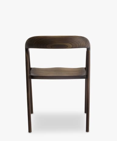 A contemporary armless chair crafted from dark walnut wood, featuring a curved backrest and a subtly sculpted seat, supported by four slender, round legs. — 3D model