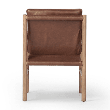 A contemporary armchair with a wooden frame and leather upholstery. The frame consists of four cylindrical legs connected by horizontal supports, forming a simple yet sturdy structure. The seat and backrest are upholstered in brown leather, with the armrests also featuring leather coverings with decorative stitching. The overall design suggests a blend of rustic and modern aesthetics. — 3D model