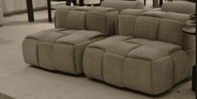 A contemporary modular lounge chair section, upholstered in a light beige textile, featuring a distinctive square-tufted design across its seat, backrest, and side. The piece exhibits a low-profile, block-like construction suitable for flexible seating arrangements. — 3D model