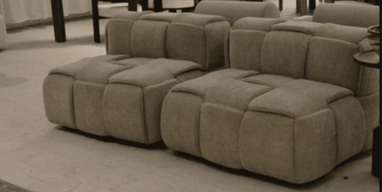 A contemporary modular lounge chair section, upholstered in a light beige textile, featuring a distinctive square-tufted design across its seat, backrest, and side. The piece exhibits a low-profile, block-like construction suitable for flexible seating arrangements. — 3D model