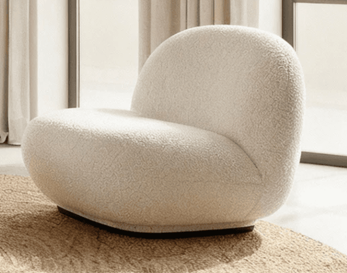 An armless lounge chair upholstered in a cream-colored boucle fabric, featuring a rounded, organic silhouette and a low profile base. — 3D model