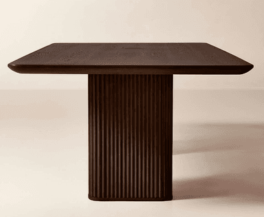 A rectangular dining table crafted from dark wood, featuring a thick, smooth tabletop. The table is supported by two substantial, vertically fluted pedestal bases, providing a modern and minimalist aesthetic. The dark finish enhances its elegant and robust presence. The ends of the tabletop show a subtle rounding. — 3D model