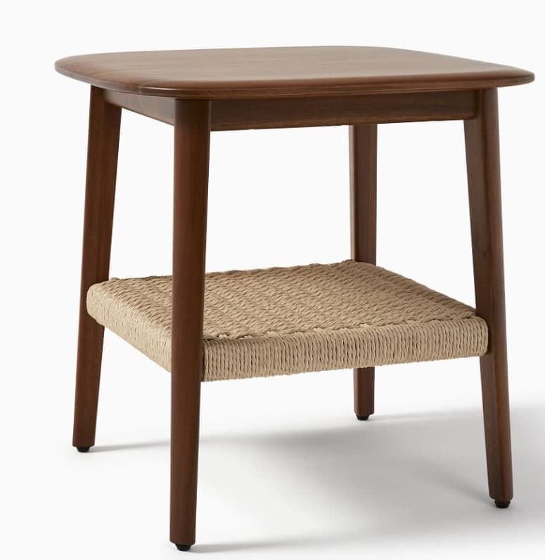 A square-topped end table with rounded corners, featuring four slender wooden legs. Below the main surface, there is a lower shelf constructed from woven natural fibers, creating a basket-like texture. The structure exhibits a minimalist design. — 3D model
