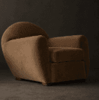A contemporary armchair with a rounded back and integrated armrests. The seat cushion is square and appears plush. The chair is supported by short, dark wooden block feet. — 3D model
