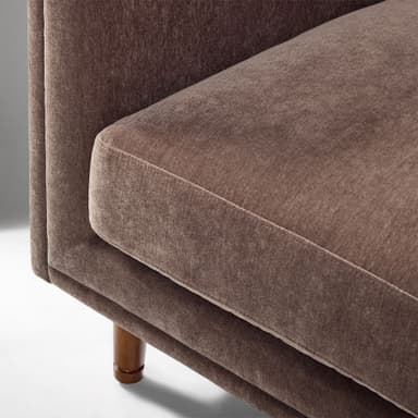 A contemporary upholstered club armchair featuring a single, removable seat cushion, integrated flared arms, and a low back, all covered in a textured, brown fabric. The chair stands on four tapered wooden legs. — 3D model