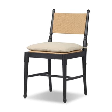 A contemporary dining chair featuring a solid black wooden frame, a natural woven rattan backrest, and a light beige fabric cushion positioned on a cane seat. The chair incorporates turned elements on its back posts and subtly tapered legs. — 3D model