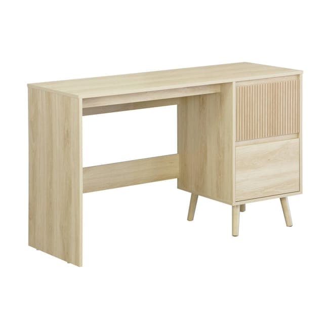 A light-colored wooden desk with a linear wood grain pattern. It features a wide, flat top supported by two legs. The left leg is a solid panel. The right side has a cabinet section with a fluted door panel above a drawer. The desk is supported by four tapered legs, with the front two legs angled outwards. — 3D model