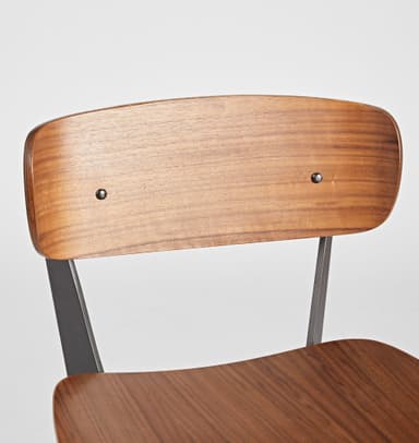 A bar stool with a backrest, featuring a wooden seat and back panel, supported by a dark metal frame. The seat and back panel appear to be made of bent wood or plywood with a wood grain finish. The frame consists of angled legs connected by a footrest at the bottom and supports for the seat and back. The design is modern and minimalist. — 3D model