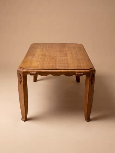 A rectangular dining table crafted from oak wood, featuring a distinctive scalloped apron and decorative carved embellishments on its corners. The table stands on four tapered legs with a subtle curve, reflecting an Art Deco or transitional design. — 3D model