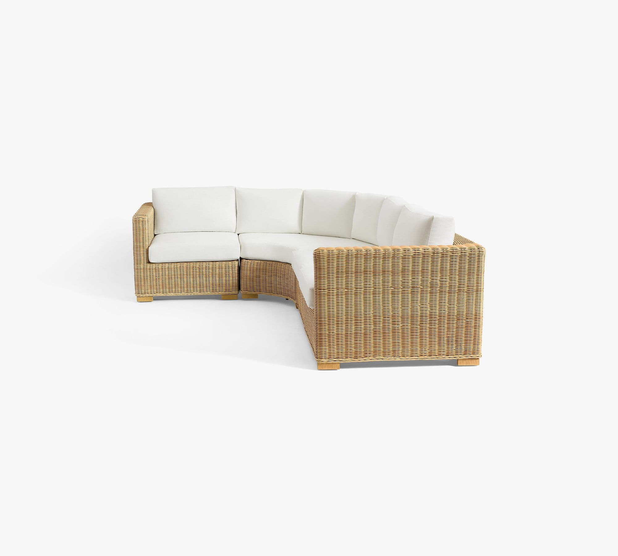 A modular sectional sofa with a curved design. The base and arms are constructed from woven wicker or rattan material, with a natural tan color. It features thick, white cushioned seating and backrests. The sofa is elevated on short, light-colored wooden legs. — 3D model