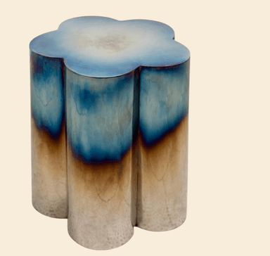 A small, modern accent table crafted from metal, featuring four integrated cylindrical columns that form a petal-shaped top and base. The metal surface exhibits a unique heat-treated iridescent finish, transitioning from deep blues and purples at the top to bronze and silver tones towards the bottom. — 3D model