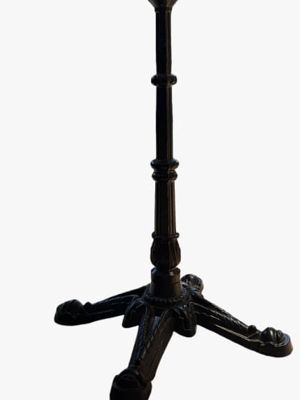 An ornate cast iron table base designed for a bistro or cafe table. It features a central fluted column with decorative rings, resting on a four-legged star-shaped base. Each leg is intricately scrolled and culminates in a paw-like foot. The base is finished in a dark, likely black, color, giving it a classic and robust appearance. The top of the column includes a flat plate with pre-drilled holes for attaching a tabletop. — 3D model