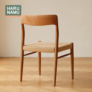 An armless dining chair constructed from light-toned natural wood, featuring a curved backrest and a square seat upholstered with woven rattan. The chair has a minimalist design with a visible wood grain and simple, sturdy legs. — 3D model