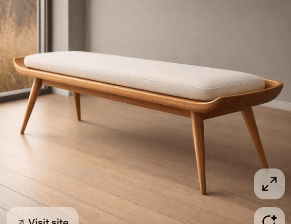 A long, rectangular bench featuring a solid light-colored wooden frame with gracefully curved edges and tapered legs. It is topped with a removable, light cream-colored upholstered cushion. — 3D model